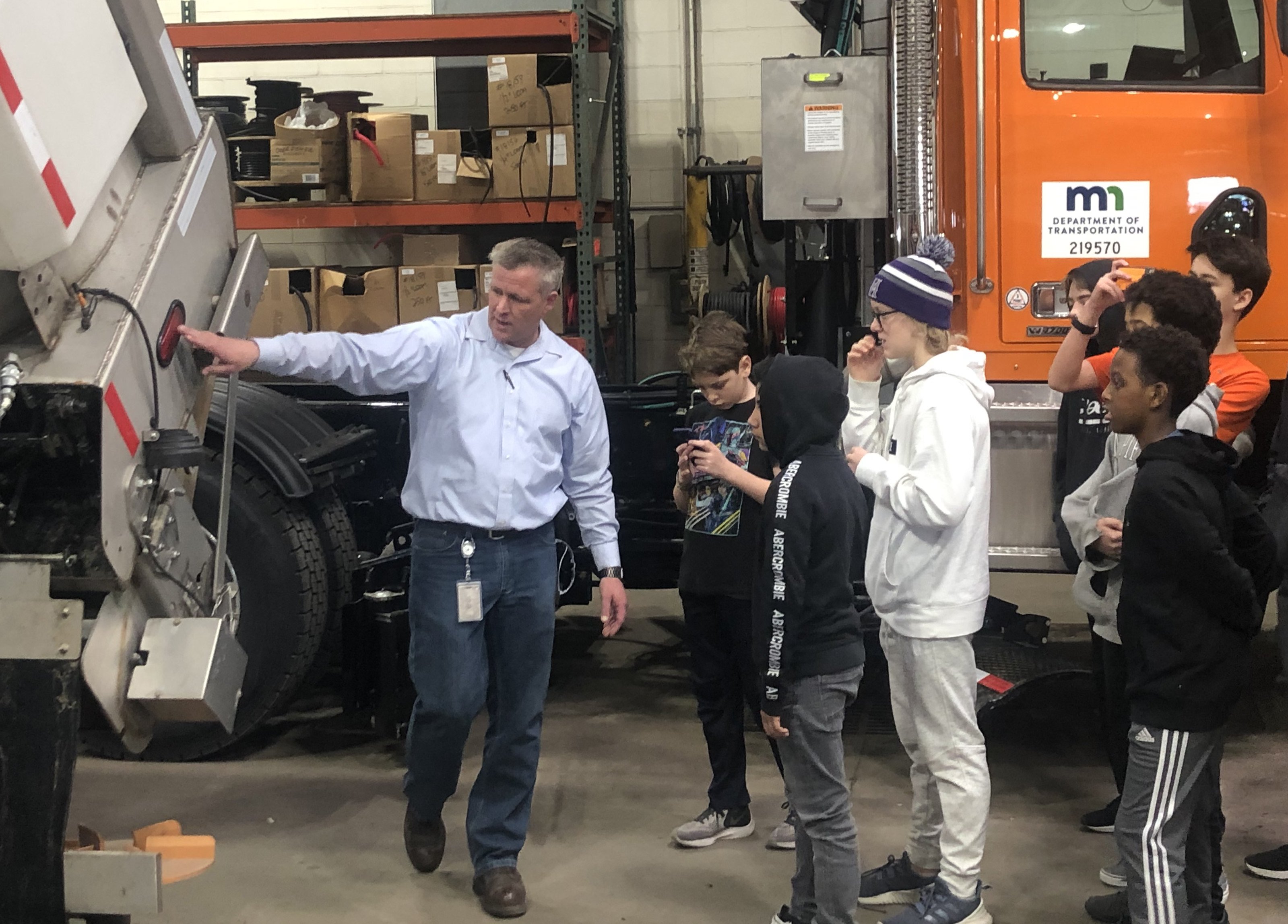 Photo: A MnDOT employee explains features on a snow plow as middle school students listen.